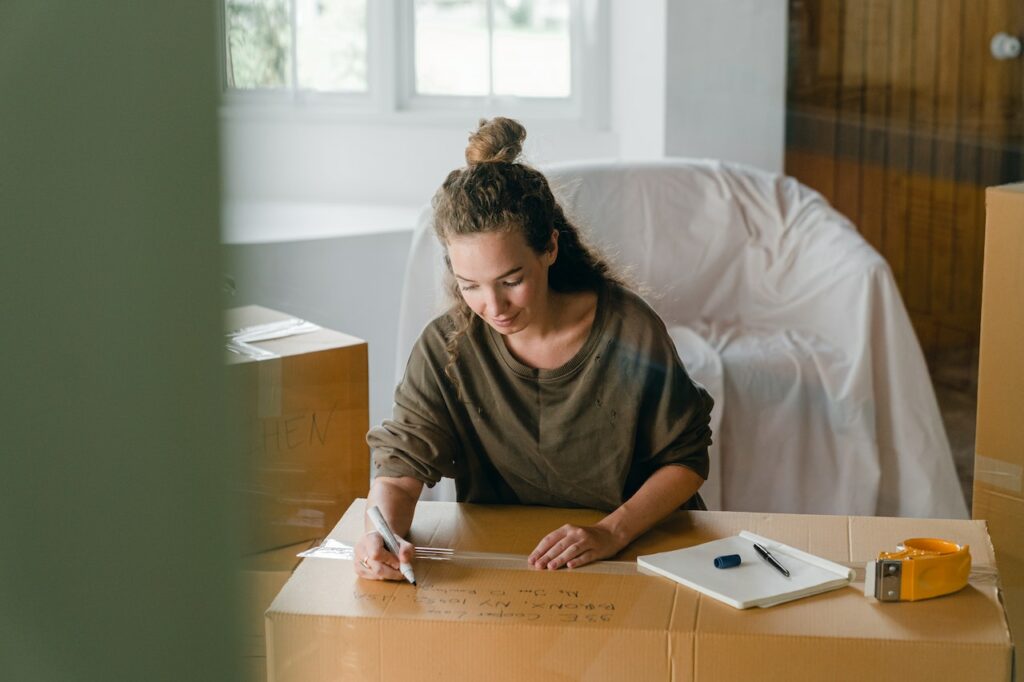 A woman labeling her moving boxes, which is the next step after you hire the right professional movers.
